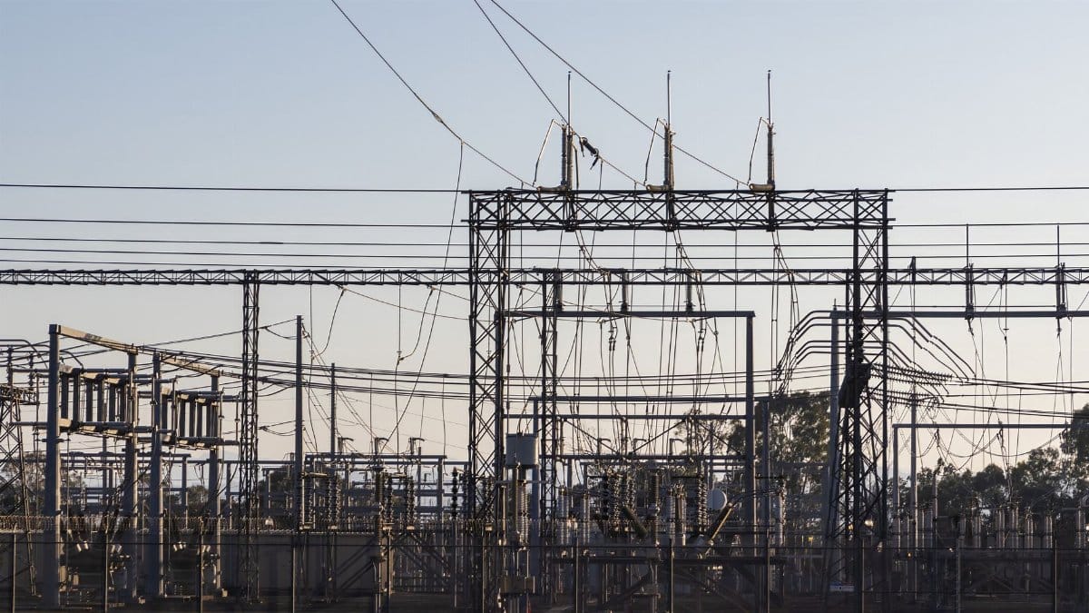 High-voltage electrical substation with steel structures and power lines at dawn.