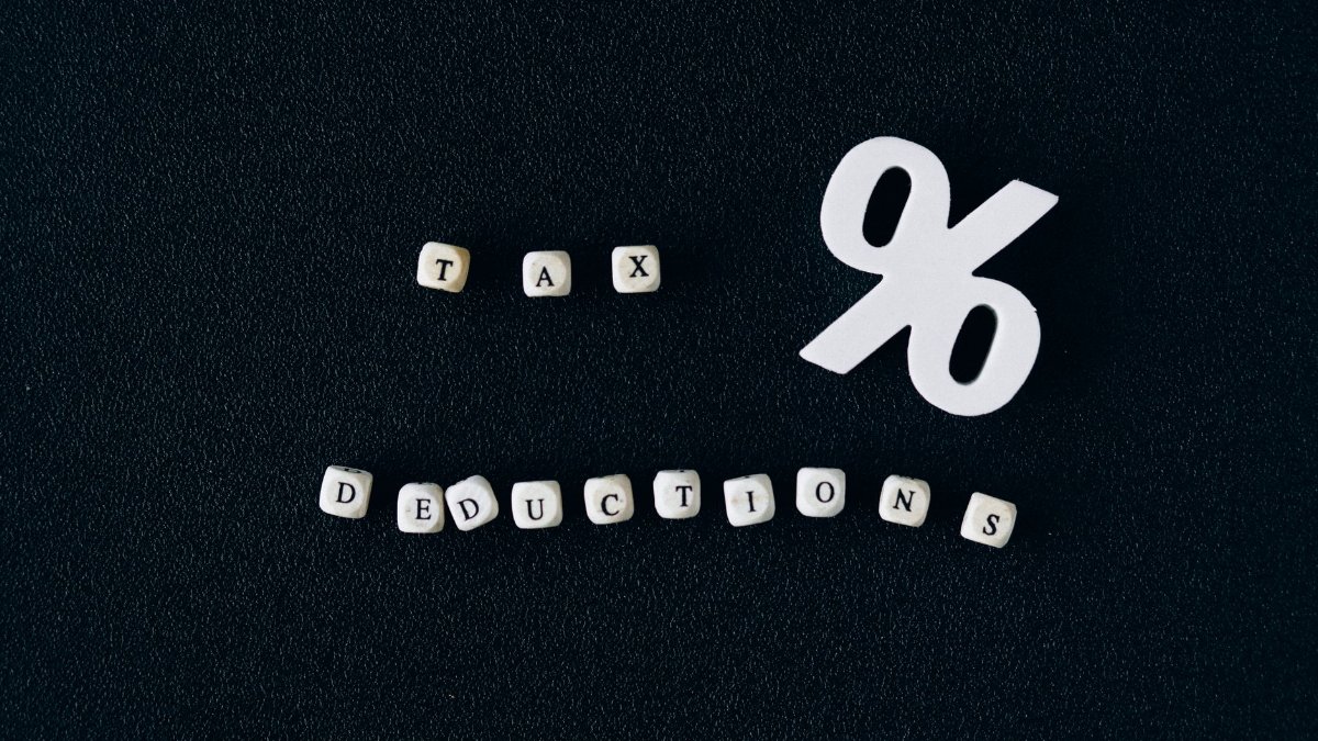 Conceptual image of tax deductions with alphabet blocks and percent symbol on black surface.