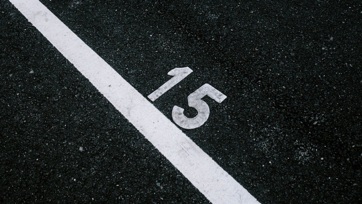 Asphalt surface with the number 15 beside a white line, ideal for transportation themes.