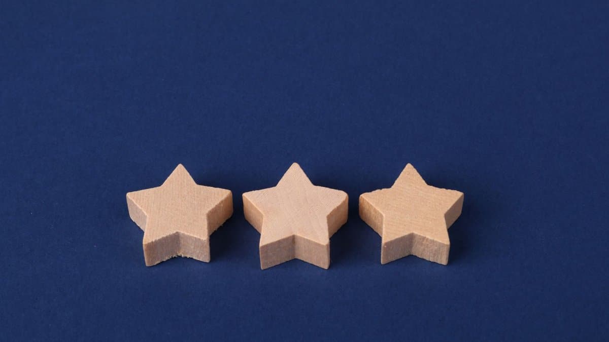 Three wooden star shapes arranged on a deep blue surface, minimalistic design.
