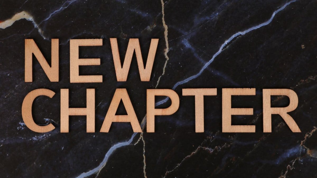 Wooden letters spelling 'New Chapter' on a dark marble background symbolize fresh beginnings.