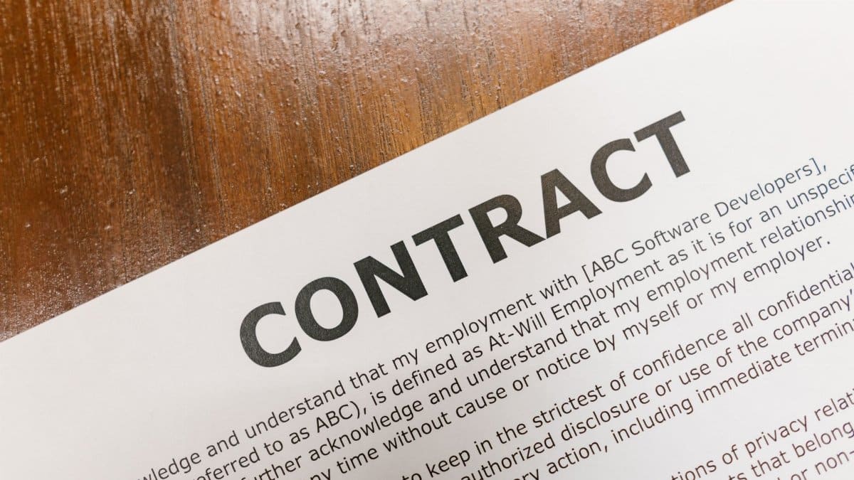 A detailed close-up of a printed contract document on a wooden table surface.