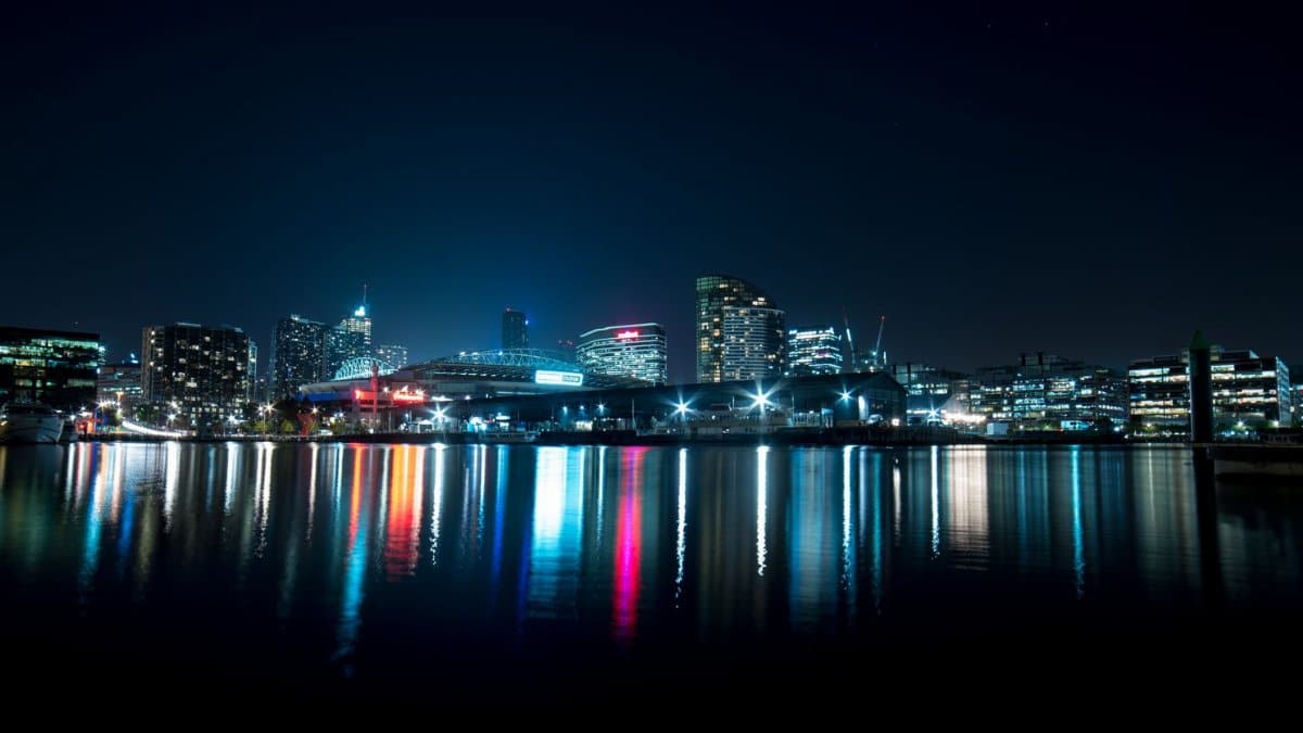 Stunning city skyline at night with colorful lights reflecting on calm water.