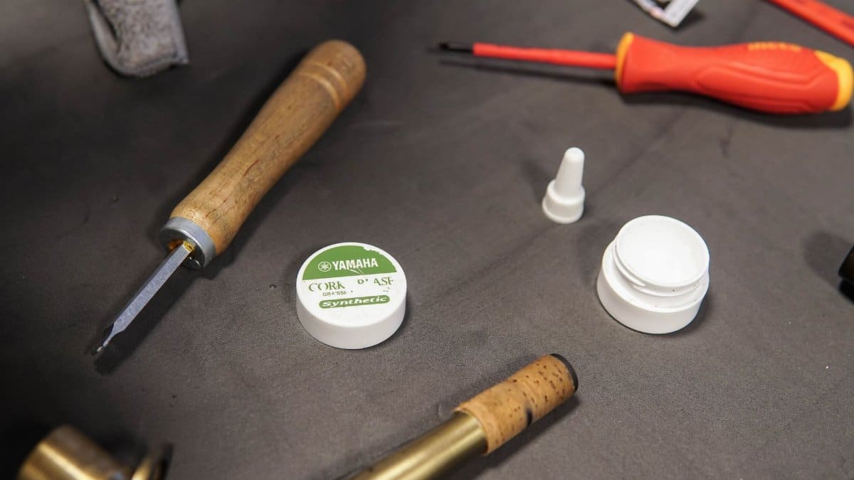 A close-up of tools and glue used in musical instrument repair on a workbench.