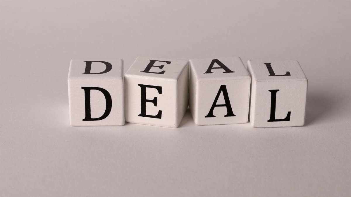Close-up of white cubes with black letters spelling DEAL on a plain background.
