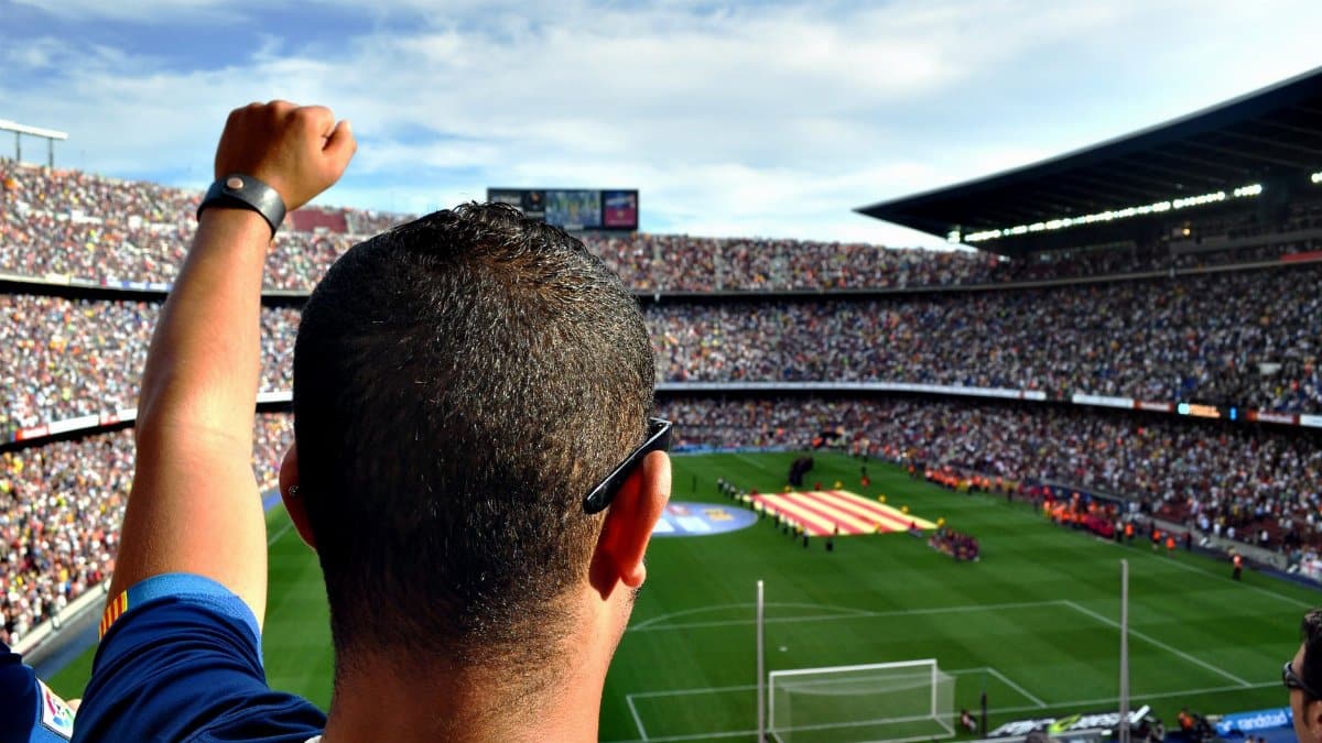 A passionate football fan cheers among a crowd at a bustling stadium, creating an electrifying atmosphere.