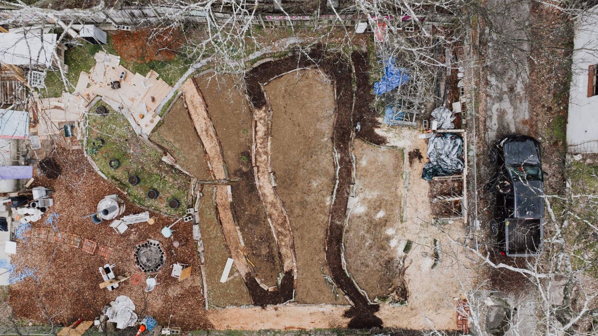 Aerial shot of a backyard construction site with various materials and earthworks.
