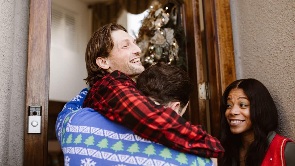 Friends warmly greet each other at a decorated doorway during Christmas, capturing the festive spirit.