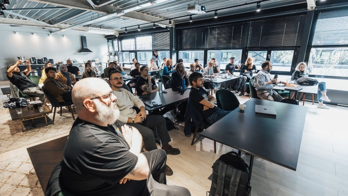 A diverse group of professionals attentively listening during an indoor business meeting in a modern conference room.