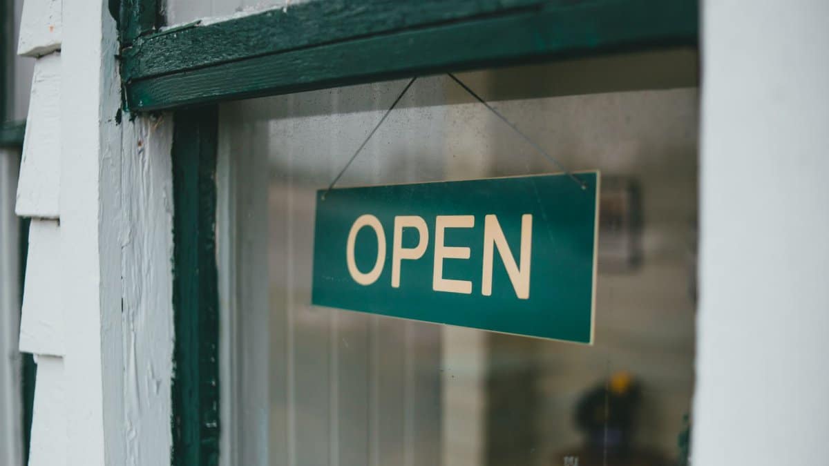 Close-up of green open sign hanging on window, inviting customers.