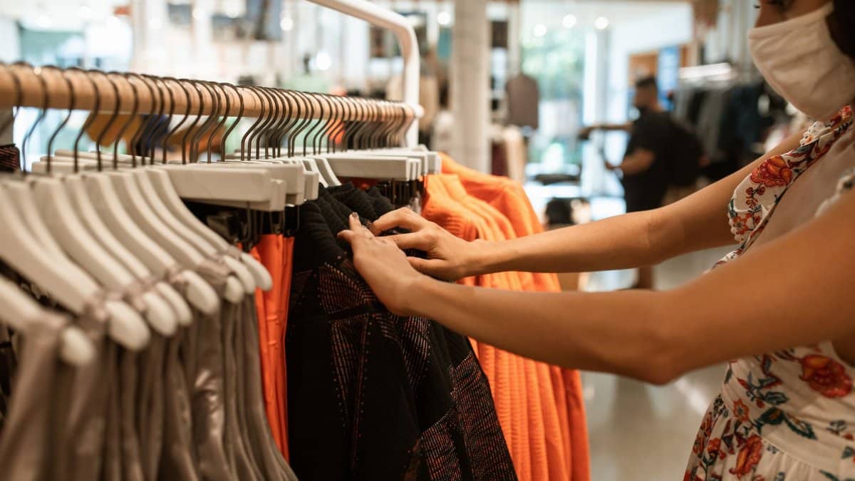A woman shops for clothes in a store while wearing a face mask, highlighting the new normal.
