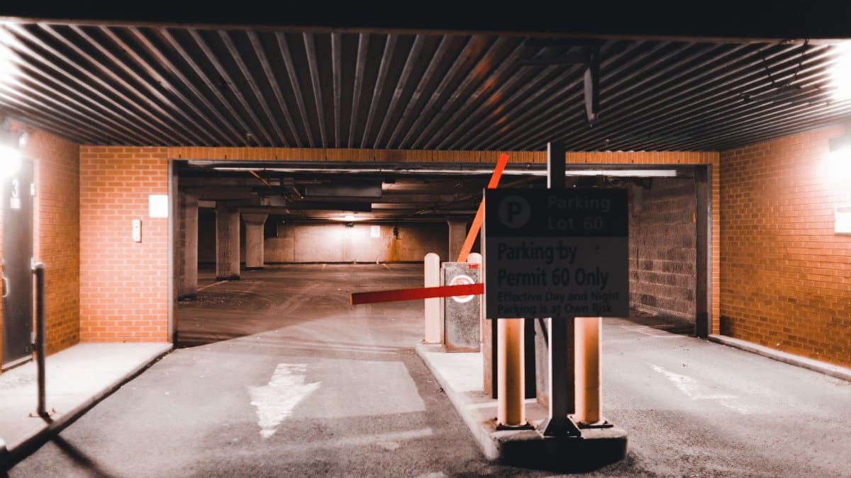 Entrance to an illuminated underground parking lot in an urban setting, highlighting modern architecture and security.