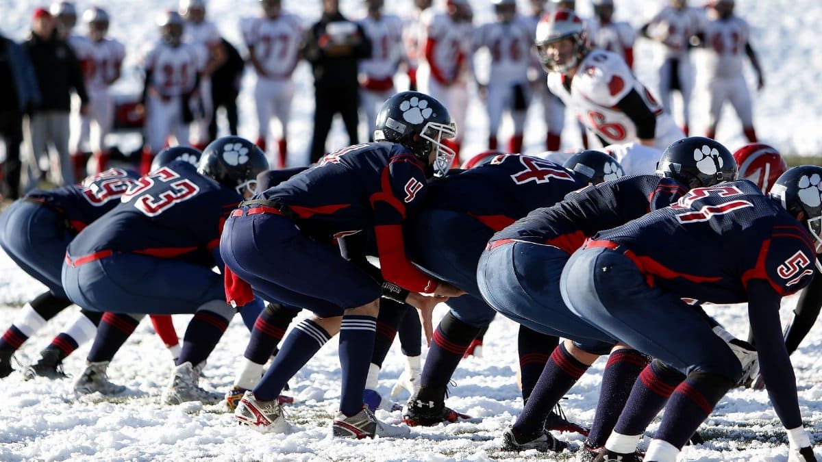 Dynamic image of athletes playing American football on a snowy field, showcasing teamwork.