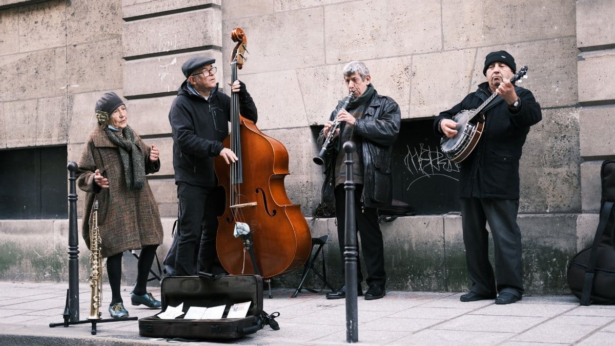 A group of street musicians performing lively music on a Parisian sidewalk.