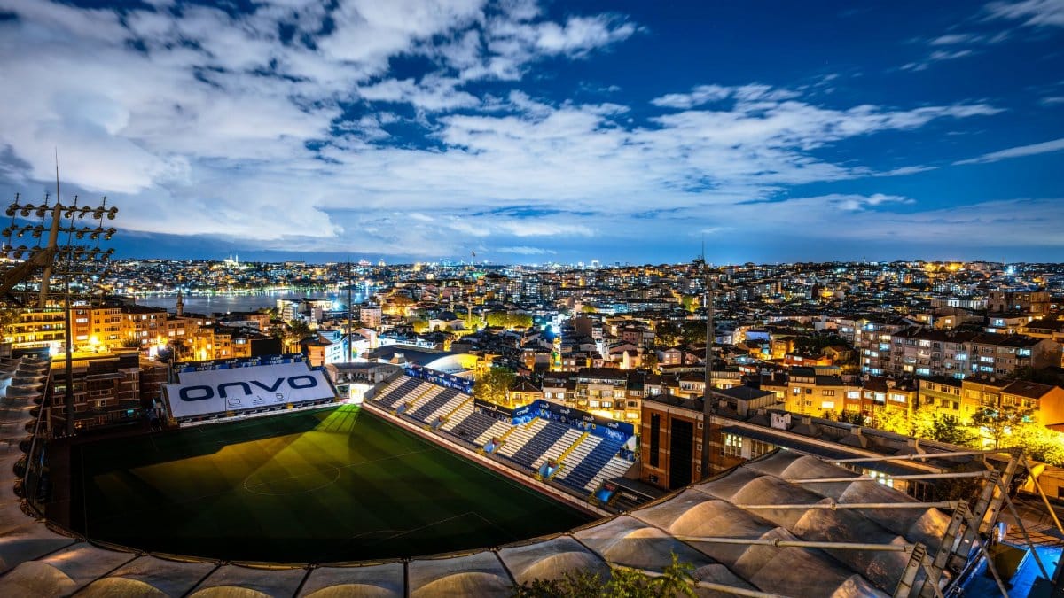 Captivating aerial view of Istanbul city and a stadium illuminated at night under a starry sky.