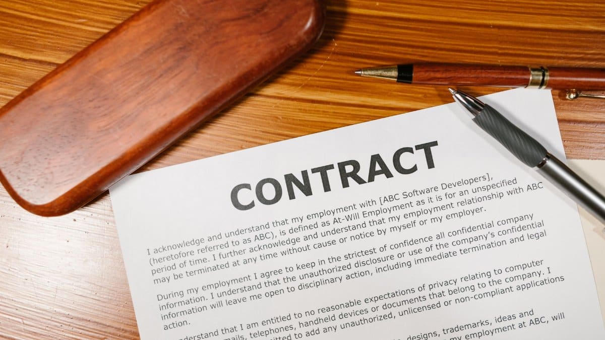 A close-up view of a contract and pen on a wooden desk, ideal for business themes.