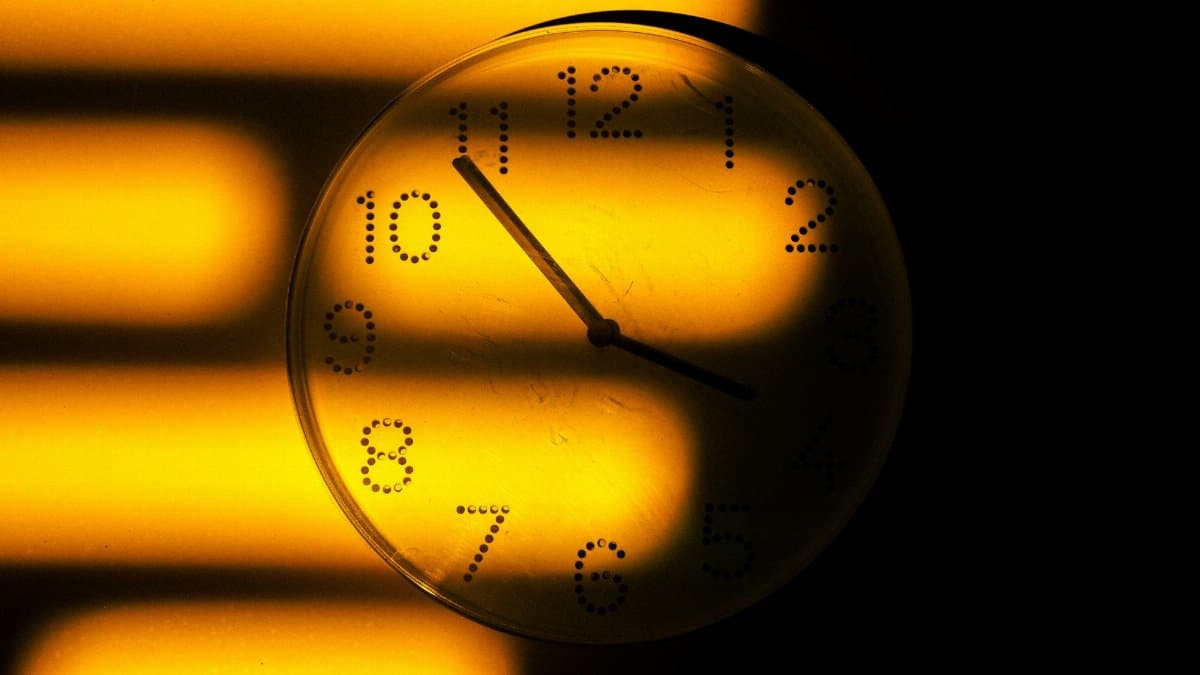 Abstract image of a wall clock with golden light and shadows, symbolizing time passage.