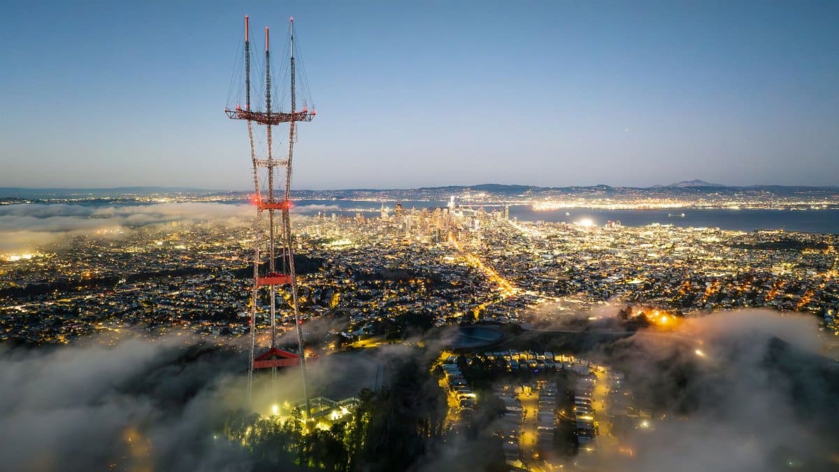 Aerial view of San Francisco cityscape with Sutro Tower above fog at twilight, showcasing an urban night scene.