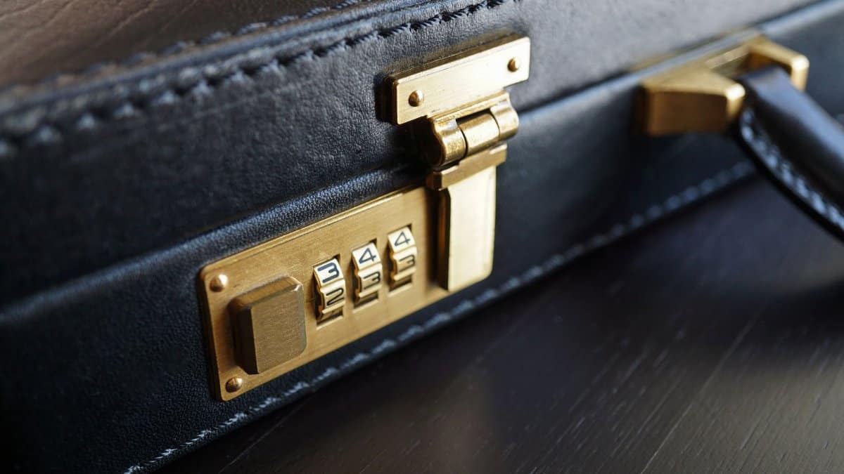 Close-up of a black leather briefcase with a brass combination lock for business security.