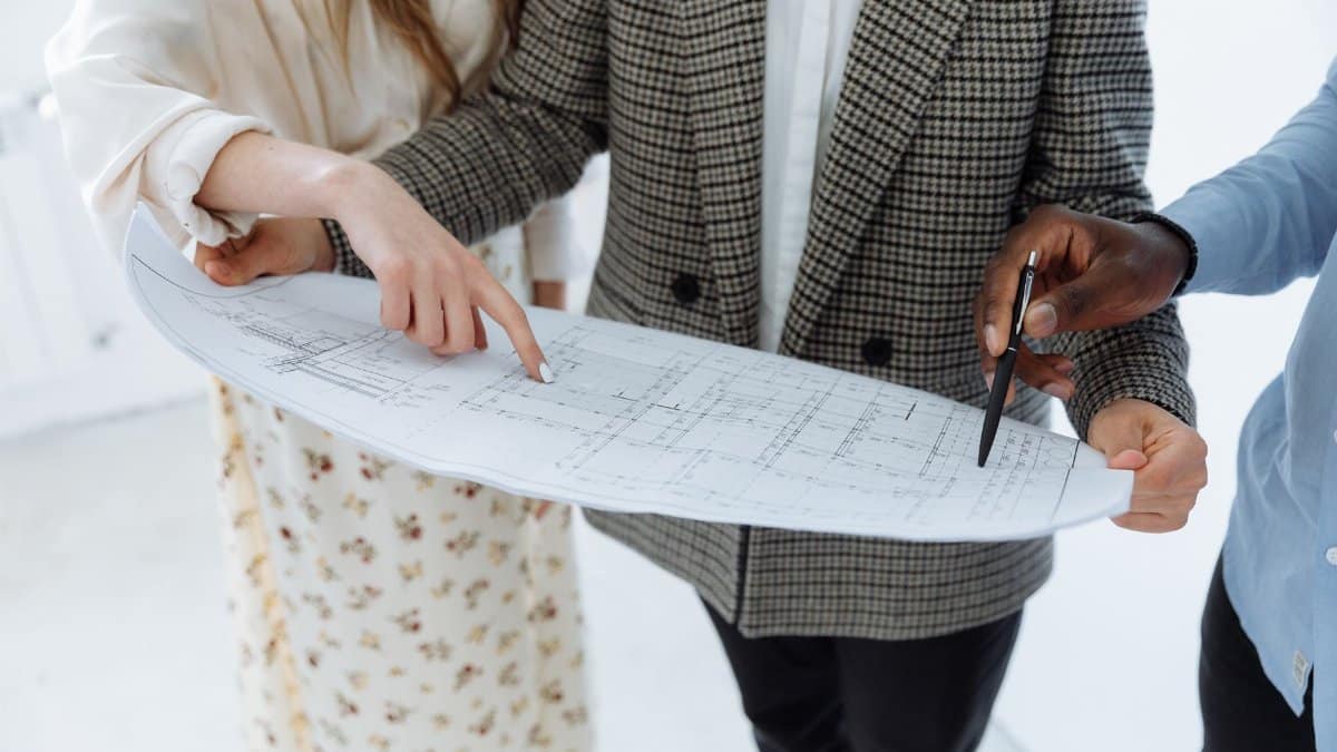 Adults reviewing detailed schematic floor plans indoors for a new building.