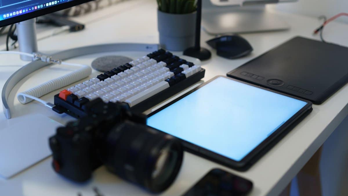 A modern home office with photography equipment, graphic tablet, and ergonomic keyboard.
