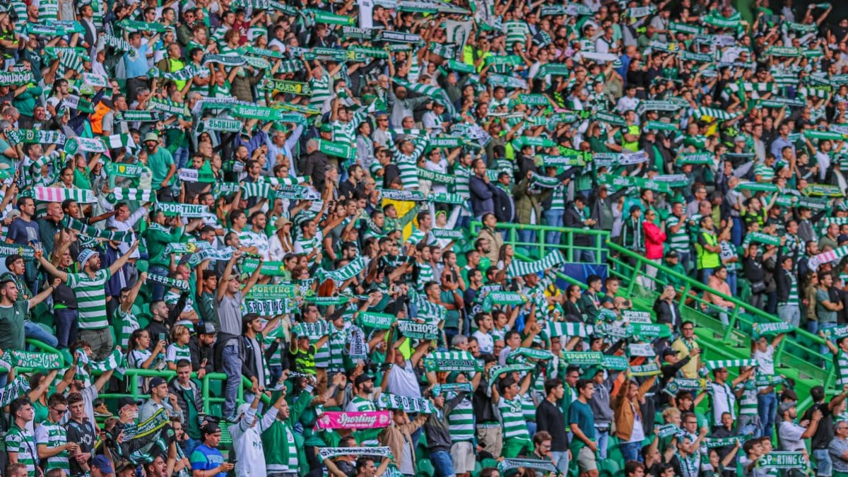 Energetic crowd of soccer fans cheering with scarves at a stadium in Lisbon, Portugal.
