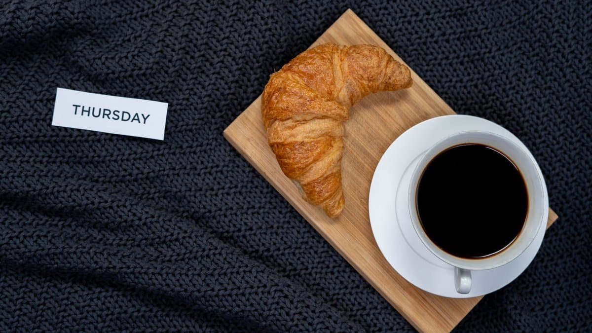 Enjoy a cozy Thursday morning with croissant and black coffee on a warm blanket.