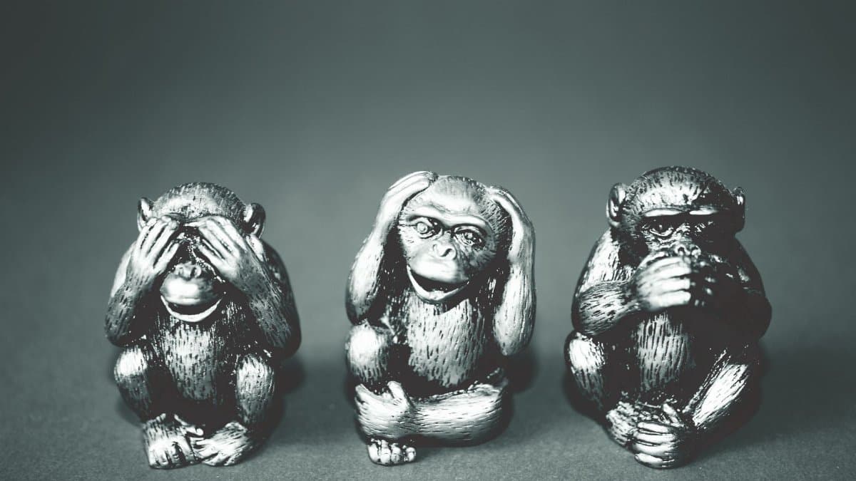 Black and white photo of three wise monkeys figurines showing the hear no evil, see no evil, speak no evil poses.