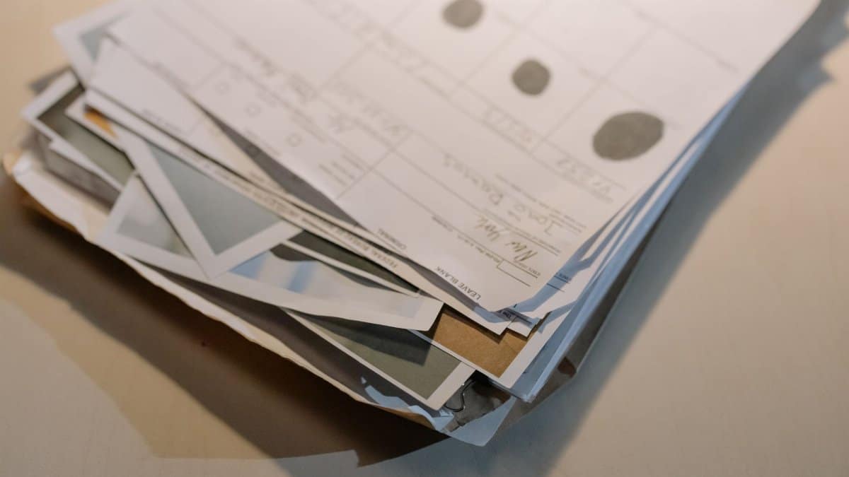 Close-up view of a stack of various papers and documents on a desk surface.