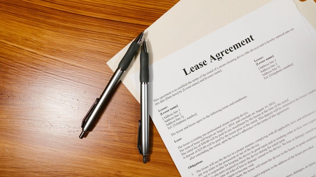 High-angle view of a lease agreement and pens on a wooden desk.