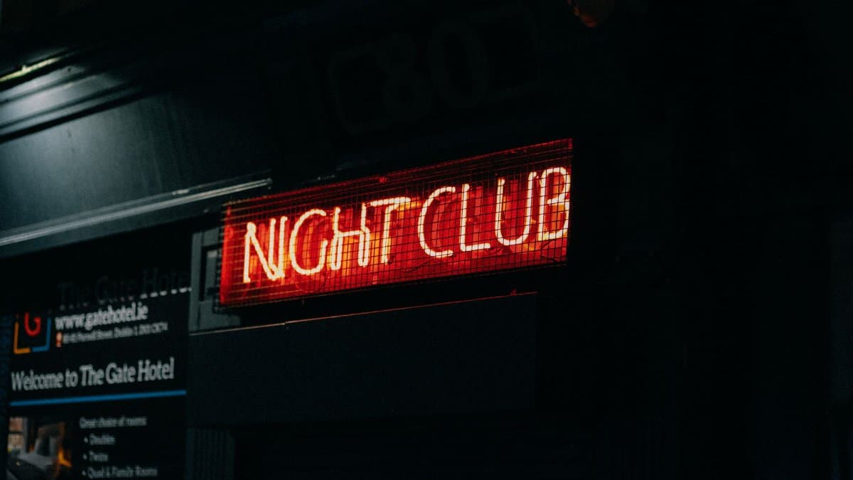 Close-up of a neon-lit 'Night Club' sign in a dark urban setting capturing nightlife ambiance.