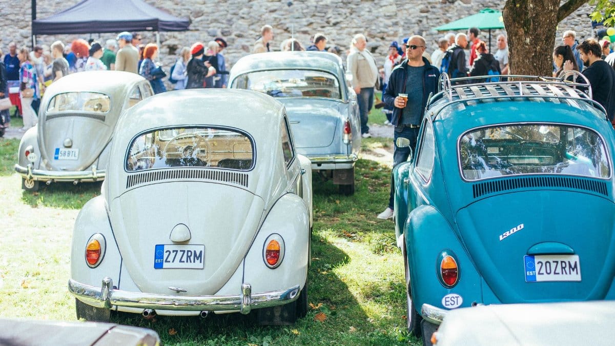 Vintage Volkswagen Beetles showcased at an outdoor event, attracting car enthusiasts.