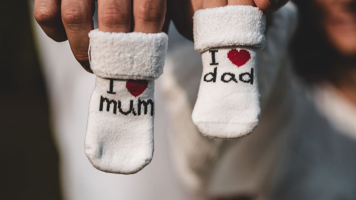 Adorable baby socks with 'I love mum' and 'I love dad' messages held by parents' hands. Perfect for family themes.