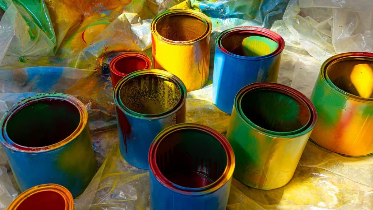 Colorful open paint cans on a plastic sheet with vibrant colors spilling over. Perfect for art and DIY themes.