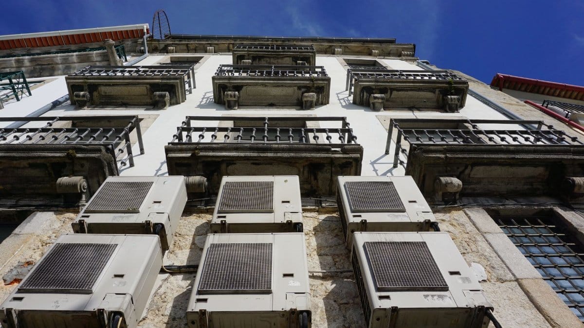 A upward view of a building facade with air conditioners and balconies in Porto.