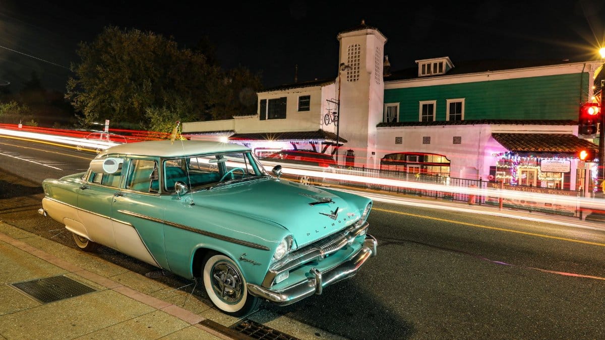 A vintage Plymouth car parked on an illuminated street in Folsom, CA, capturing vibrant urban night life.