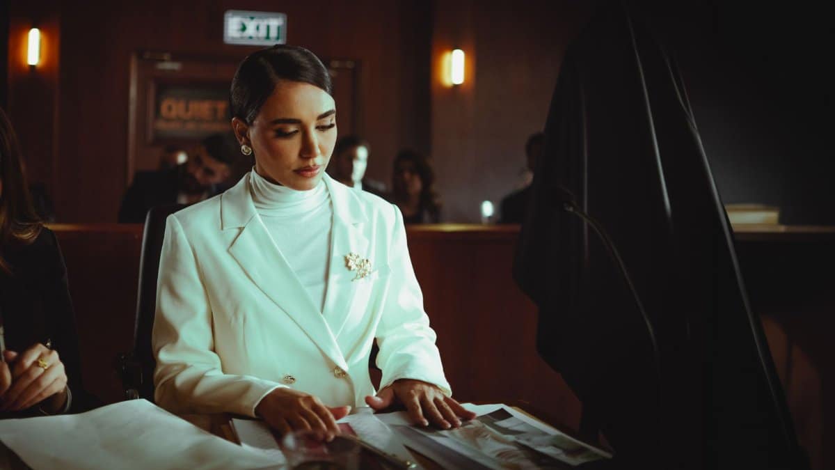 Elegant woman in a courtroom setting, reviewing documents with focus and confidence.