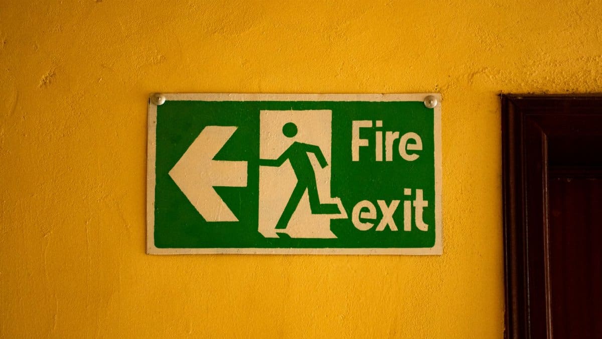 Fire exit sign on a yellow wall, indicating safety and emergency exit direction.