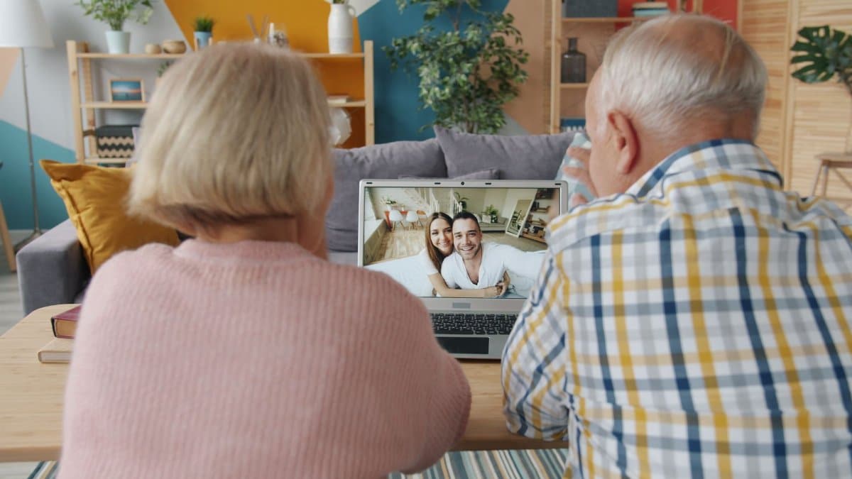 Senior couple enjoying a video call with family members on a laptop in a cozy living room.