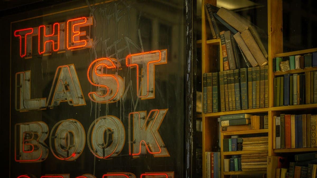 Vibrant neon sign of The Last Bookstore with a backdrop of books in Los Angeles.