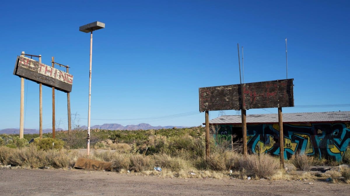 Rustic scene of old, abandoned signs in a barren desert setting, highlighting decay.