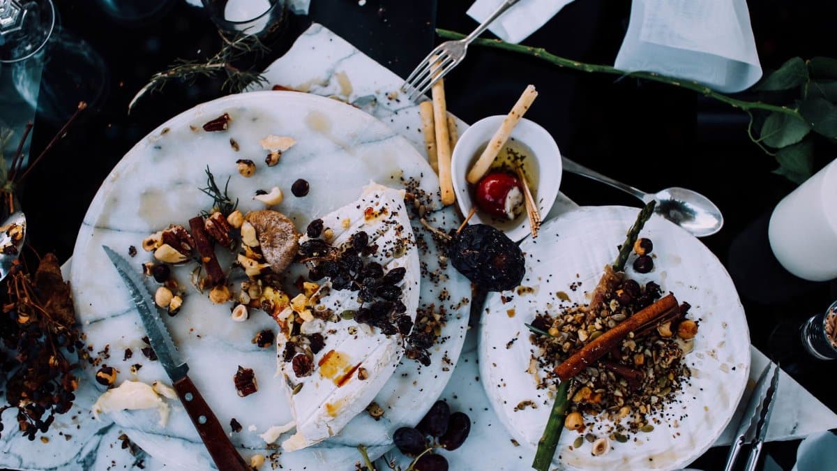 From above of plates with remains of various dishes left after festive dinner on table with cutlery and flowers