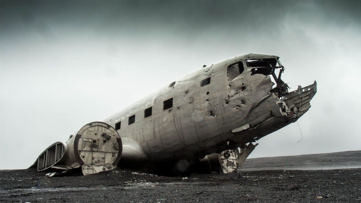 A dramatic photo of a derelict plane wreck on a remote, deserted landscape.