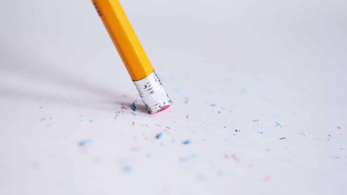 Macro shot of a yellow pencil erasing on paper with eraser shavings.