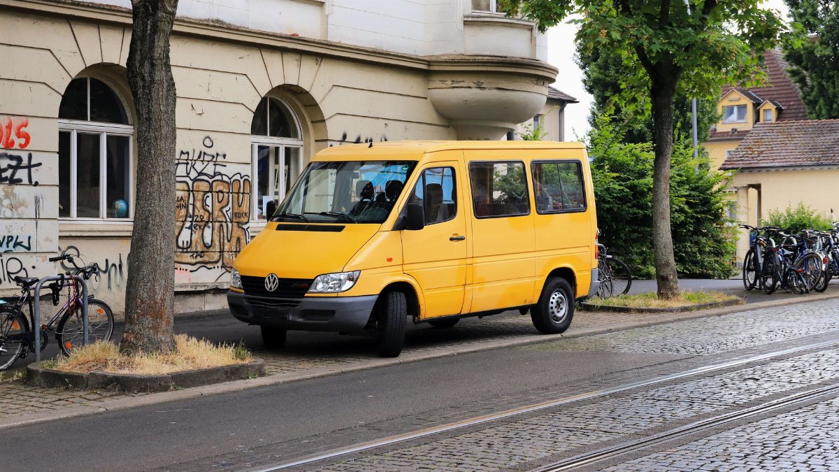 A bright yellow van parked on a cobblestone street in Kassel, Germany, surrounded by bicycles and old architecture.
