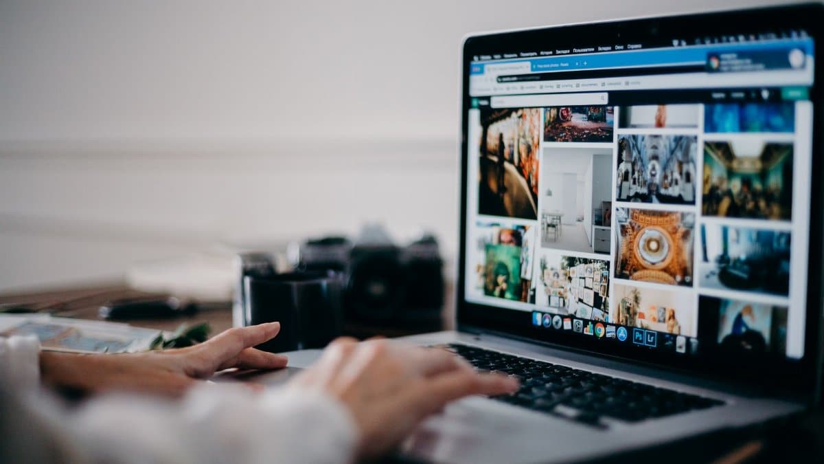 Close-up of hands using laptop for image searching and browsing digital photo gallery.