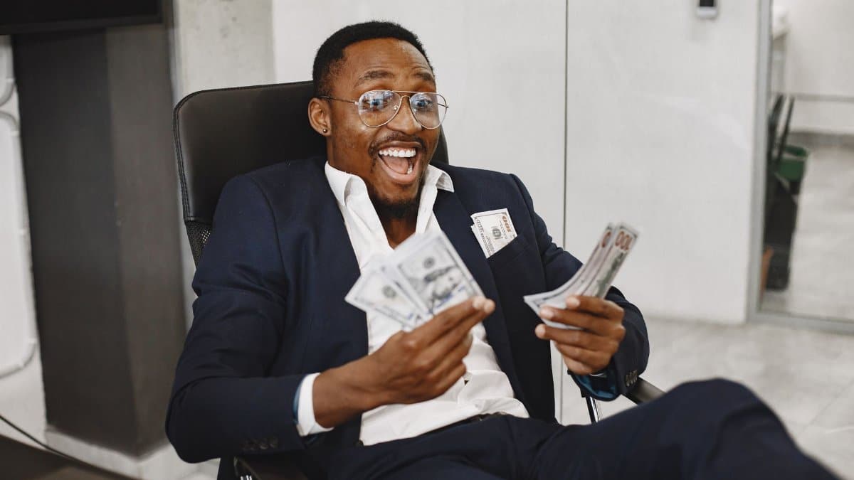Joyful businessman in suit holding dollar bills, symbolizing success and financial achievement.