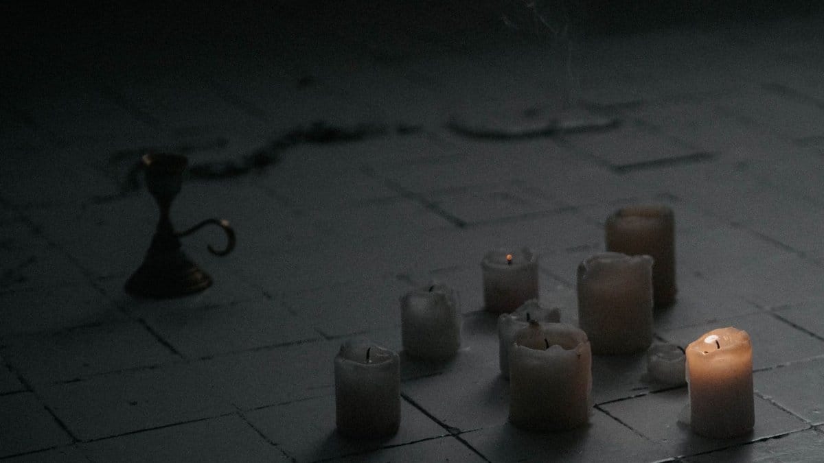 Atmospheric candles lit on a dark tiled floor, evoking a sense of mystery.