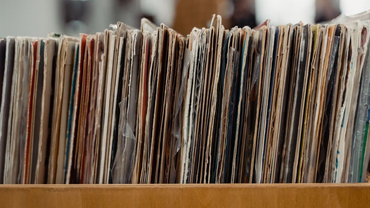 Stack of vintage vinyl records stored in a wooden crate, showcasing a retro vibe.