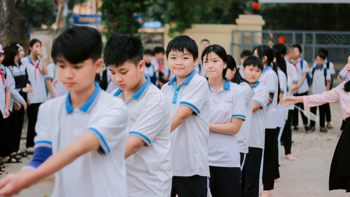 Group of students in uniforms lined up outdoors, engaged in an activity.